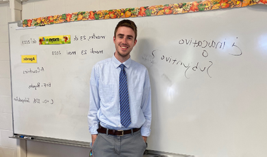 Jake Murray stands in front of a white board in a classroom.